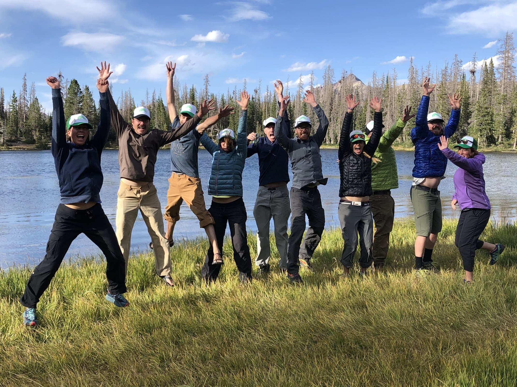 The Inspired Summit guide team jumping for joy beside an alpine lake